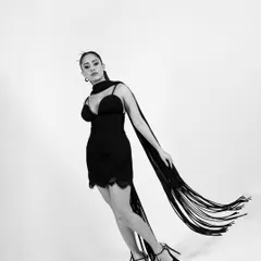 This dynamic pose captures the movement of the fringe scarf, adding a sense of energy and grace to the black and white composition.