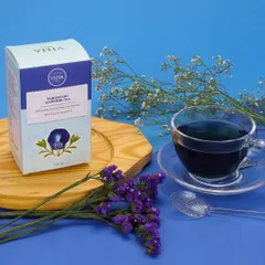 A styled product shot for Darjeeling Sapphire Tea, featuring the packaging alongside a cup of the distinctive blue tea. The composition is enhanced with complementary blue and white floral props to create an elegant theme.