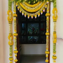 Another view of the traditional door decor with yellow flowers and lotus buds. This design is perfect for creating a welcoming entrance for guests during a festival or pooja.