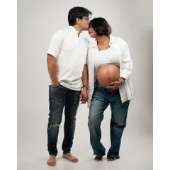 A standing portrait of a couple in casual jeans and white shirts, holding hands and sharing a sweet moment.