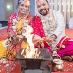 The couple sits before the sacred fire (homa), their happy faces illuminated by the flames. This is a central part of the wedding ceremony, symbolizing their union.