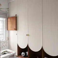 This custom wardrobe was designed for a compact kid's room. The playful, scalloped-edge doors and fluted texture conceal ample storage, while the open niche is perfect for displaying favorite toys.