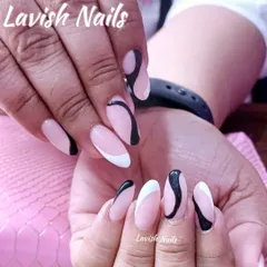 A similar abstract design with flowing black and white lines on almond-shaped nails, creating a sense of movement and style.