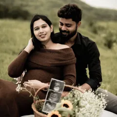 A lovely picnic scene, with the couple sitting together and looking at the sonogram pictures. The basket of flowers adds a beautiful touch of color.