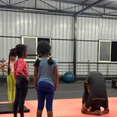 Leading by example is important. Here, the kids watch as I demonstrate a headstand variation, showing them the focus and control required for balance skills.
