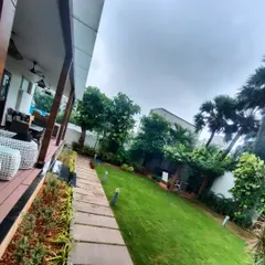 A long view of a residential backyard we landscaped. The healthy green lawn is bordered by a stone path and a variety of trees and shrubs.