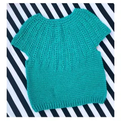 Here is the Goldenrod Sweater, a beautiful short-sleeved top made with soft cotton yarn. The textured stitch work gives it a lovely feel, and it's perfect for a casual day out. This piece is laid flat to show the full body construction before it's worn.