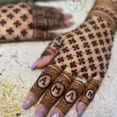 Here, the name 'AMAN' is beautifully written across the fingers, with each letter framed like a jewel. This is a popular style for engagement and bridal mehndi.