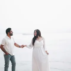A bright and airy shot of the couple walking along the riverbank. The simple white outfits and natural setting create a feeling of effortless romance.