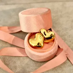 This Valentine's Day, say it with style. These puffy gold heart earrings, nestled in a pink velvet box, are the perfect way to show your love.