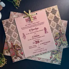 This invitation suite features inserts with laser-cut holes for a ribbon binding, set against a background of traditional elephant and jali patterns.