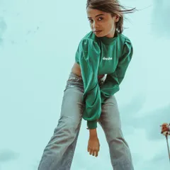 Wind in the hair and a direct look at the camera. This image from the green top series has a candid, energetic feel, showcasing a different side of the model's personality.