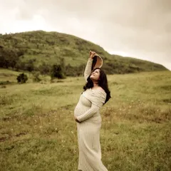 A graceful and elegant pose. The mom-to-be stands in a field, holding her hat up to the sky, her dress flowing around her. It’s a portrait of strength and beauty.