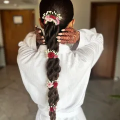 A behind-the-scenes look at Neha's stunning floral braid. Even in her getting-ready robe, the hairstyle is a work of art, showcasing the beauty of her long, natural hair.