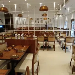 The interior of the restaurant, showing the arrangement of tables and chairs I provided. The space features a mix of seating, including upholstered chairs and wooden benches, to accommodate different group sizes.