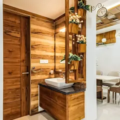 This washbasin unit features beautiful wood panelling on the walls and vanity. A wooden partition with built-in planters adds a touch of nature and separates the space from the dining area.