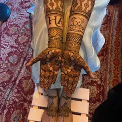 A full view of the personalized bridal mehendi, showing the custom initials and teddy bear on the arms, along with matching elegant designs on the feet.