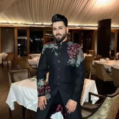 This black Bandhgala suit features asymmetrical floral embroidery in rich maroon and subtle green tones. It's a contemporary twist on a classic silhouette, perfect for a sangeet or reception.