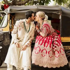 A fun and quirky portrait celebrating a Gujarati and Italian cross-cultural wedding, with the couple sharing a kiss on a classic Mumbai auto-rickshaw.