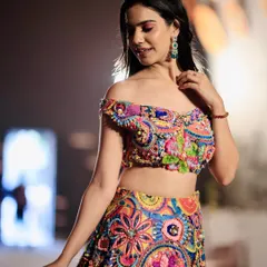 A close-up look at the intricate threadwork and off-shoulder design of this vibrant lehenga. I ensure that the fine details of the garment are clearly visible.