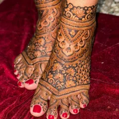 Another angle of the intricate lotus feet design, set against a rich red velvet background. The dark henna paste stands out beautifully, promising a gorgeous stain.