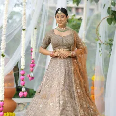 A full-length shot of the bride in her gorgeous pastel lehenga. The makeup is soft and glowing, with a red flower in her hair adding a beautiful pop of color.