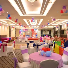 A full view of a banquet hall prepared for a birthday party. This shows our service for decorating the entire venue, including tables, chairs, and ceiling balloons.