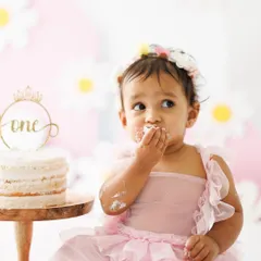 A close-up of the messy fun. With frosting on her face and fingers, this little one is fully enjoying her first birthday cake experience. These are the moments of pure, uninhibited joy.