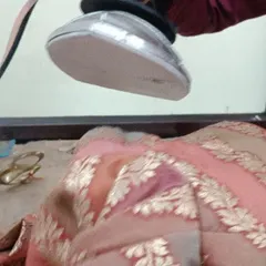 A close-up of the steam iron being used on a brocade fabric. This process sets the seams and gives the garment its final shape and structure.