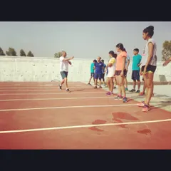 A coach briefs the players before a set of reflex and speed drills on the athletics track. Proper form and technique are emphasized even during our outdoor fitness sessions.