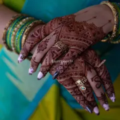 A close-up shot of the rich henna stain, adorned with rings. You can see the depth of color and the crispness of the lines, even in the most detailed parts of the design.