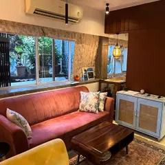 This view shows the comfortable seating area with a mix of textures and colors. The custom light blue cabinet with cane doors adds a unique touch to the room's decor.
