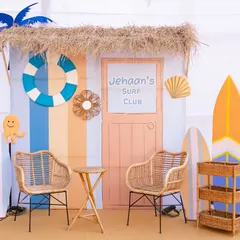 I love creating themed photo booths. For this party, I designed 'Jehaan's Surf Club', a charming little beach shack with surfboards and rattan chairs, perfect for guests to take pictures.