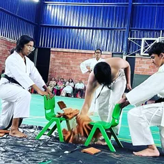 A student demonstrates immense focus and power by breaking a stack of tiles with a hand strike during a belt exam demonstration.