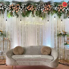 Modern romance defined. This reception stage features a 'Together Forever' neon sign, a canopy of tropical leaves and peach roses, and hanging Edison bulbs for a warm, contemporary glow.