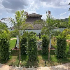 The "after" shot of the same gazebo. Now it is a stunning centerpiece, surrounded by a circular driveway, vertical gardens, and elegant foxtail palms.