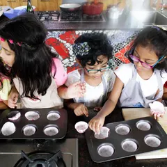 Future bakers in the making. A group of girls carefully prepares their cupcakes, learning the basics of baking in a fun and supportive setting.