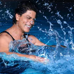 A throwback shot of Shahrukh Khan, capturing a moment of pure joy and energy. The dynamic water splash and genuine smile make for a timeless and lively editorial portrait.