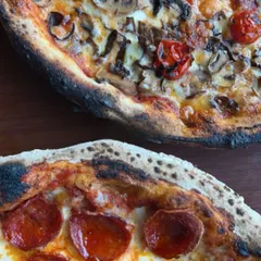 A side-by-side of two of our most popular pizzas, one with mushrooms and roasted tomatoes, the other a classic pepperoni.