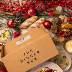 Our signature packaging is designed to protect the integrity of your meal and build anticipation for the feast within. Here, our box is pictured as part of a festive tablescape, ready to be the star of the celebration.