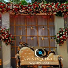 A beautiful outdoor Mehendi stage setup with a backdrop of red and white florals. The elegant draping and hanging bells add a traditional touch to the bright and airy design.