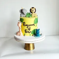 This intimate jungle-themed cake was perfect for Rajveer's first birthday. It features cute, handcrafted fondant animals like an elephant, lion, giraffe, and hippo on a vibrant yellow ganache cake.