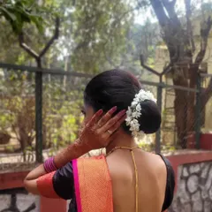 A classic and neat low bun hairstyle, elegantly adorned with a string of fresh white gajra (jasmine flowers). This traditional Indian hairstyle is perfect for pairing with a saree and is a popular choice for weddings and pujas.