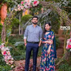 A couple poses in front of a rustic floral arch made of woven branches, a beautiful and natural frame for a romantic portrait.
