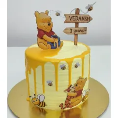 A sweet Winnie the Pooh cake for Vedansh's 3rd birthday. This vanilla cream cake features a honey drip effect and adorable characters from the Hundred Acre Wood. It's completely chemical-free and preservative-free.