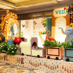 A roaring good time for Ved's 'Wild One' birthday! This setup features a storybook backdrop, a cute animal train, and balloon garlands, creating a playful and imaginative jungle scene indoors.