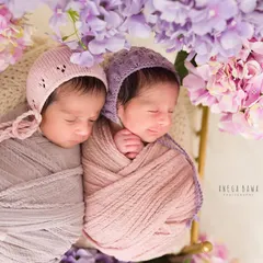 Sleeping soundly under a canopy of flowers. This overhead shot of newborn twins in soft bonnets showcases the artistry and detail that goes into every newborn session.