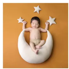 A happy dreamer on a crescent moon. This portrait against a warm mustard background captures a sweet, sleepy smile, making for a truly heartwarming image.