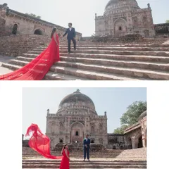 A dramatic, sweeping shot at a historic Delhi monument, with the bride's vibrant red dress flowing in the wind. We use grand architecture to frame your love story, creating powerful and timeless portraits.