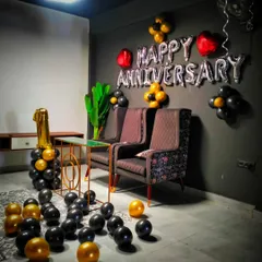 A stylish and modern first-anniversary decoration. The black and gold theme, "Happy Anniversary" foil balloons, and a large "1" balloon make for a chic and celebratory corner.